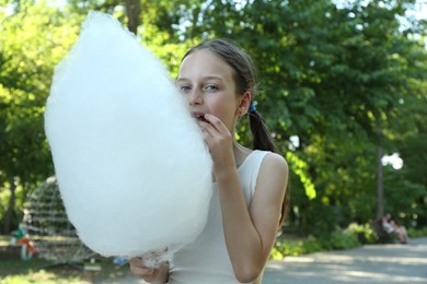 Photo of Little girl eating sweet cotton candy in park