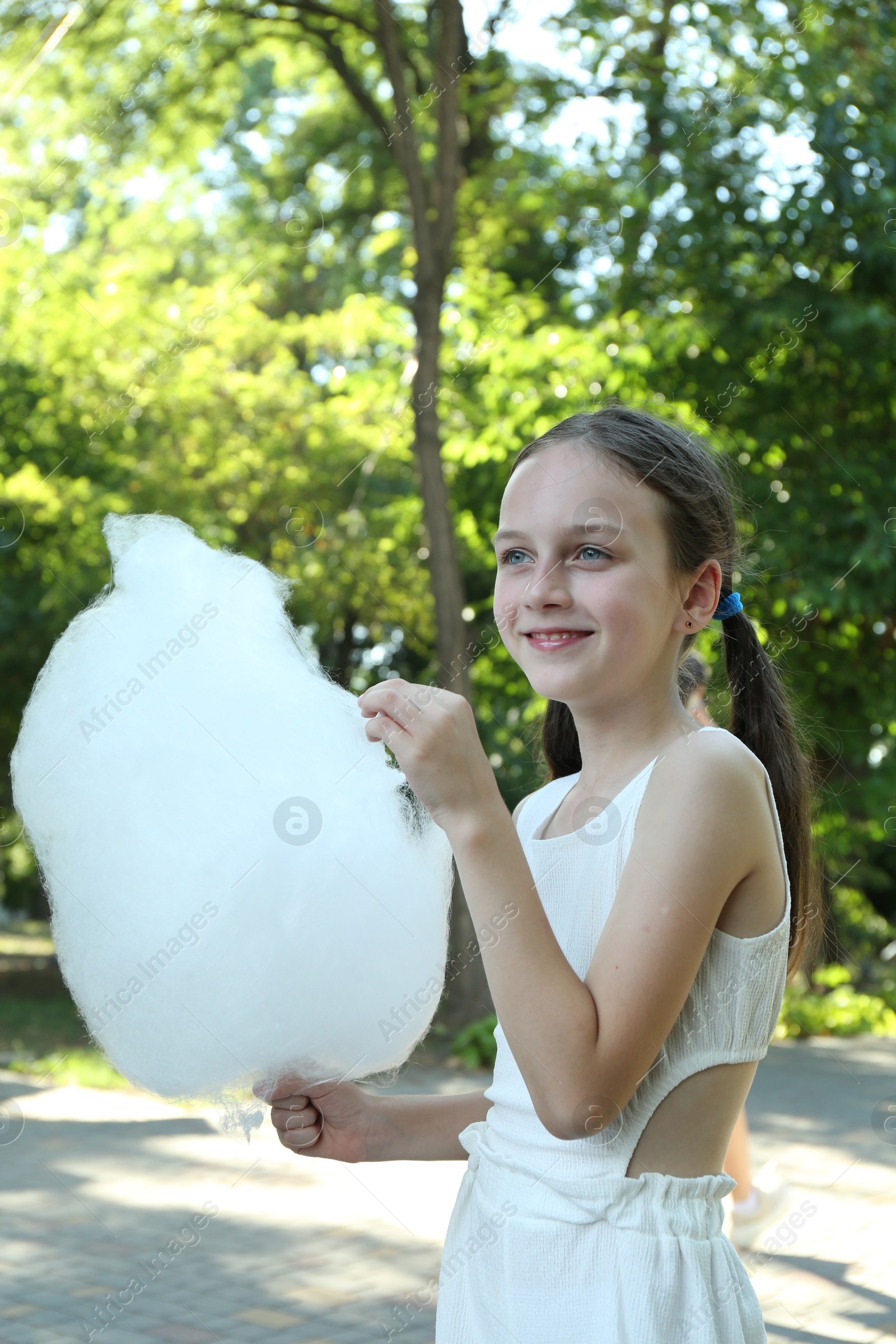 Photo of Happy girl with sweet cotton candy in park