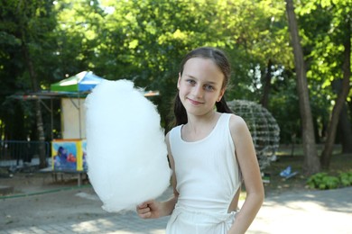 Photo of Portrait of little girl with sweet cotton candy in park