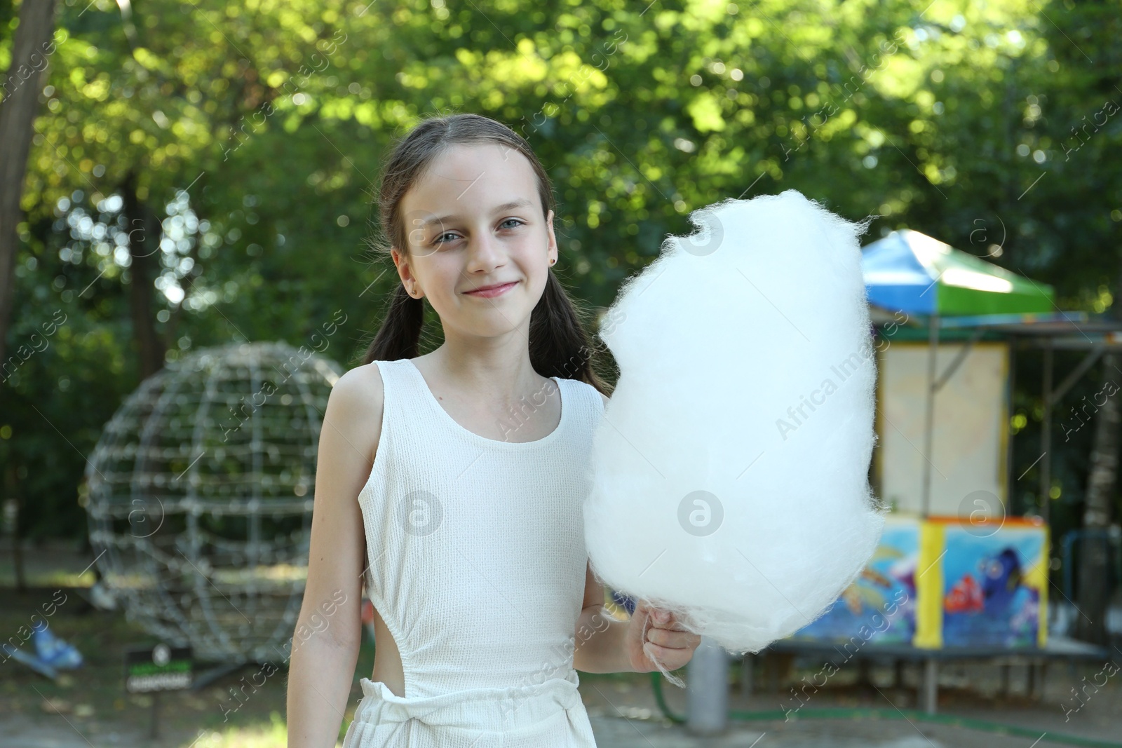 Photo of Portrait of little girl with sweet cotton candy in park