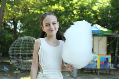 Photo of Portrait of little girl with sweet cotton candy in park