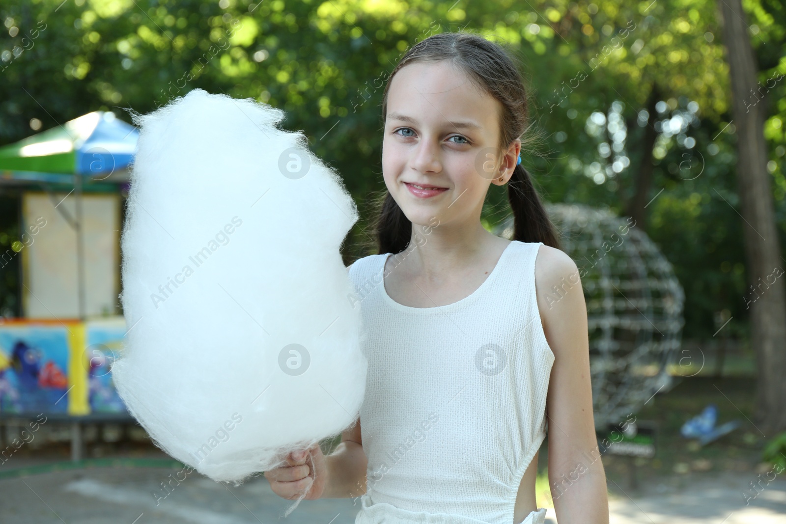 Photo of Portrait of smiling girl with sweet cotton candy in park