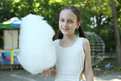 Photo of Portrait of smiling girl with sweet cotton candy in park