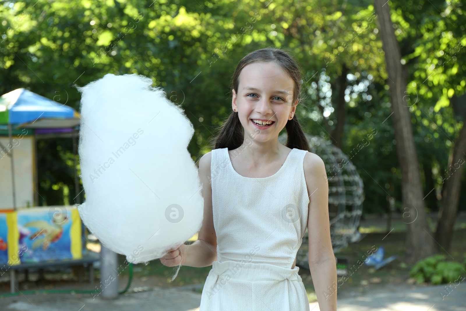 Photo of Portrait of happy girl with sweet cotton candy in park