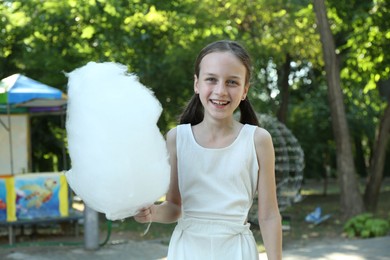 Photo of Portrait of happy girl with sweet cotton candy in park