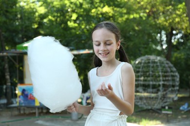 Photo of Portrait of smiling girl with sweet cotton candy in park