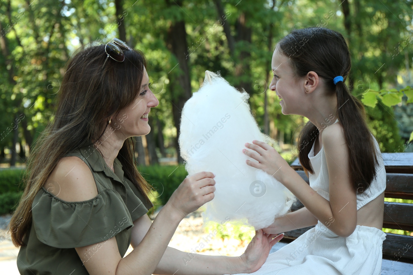 Photo of Happy mother and daughter eating sweet cotton candy in park