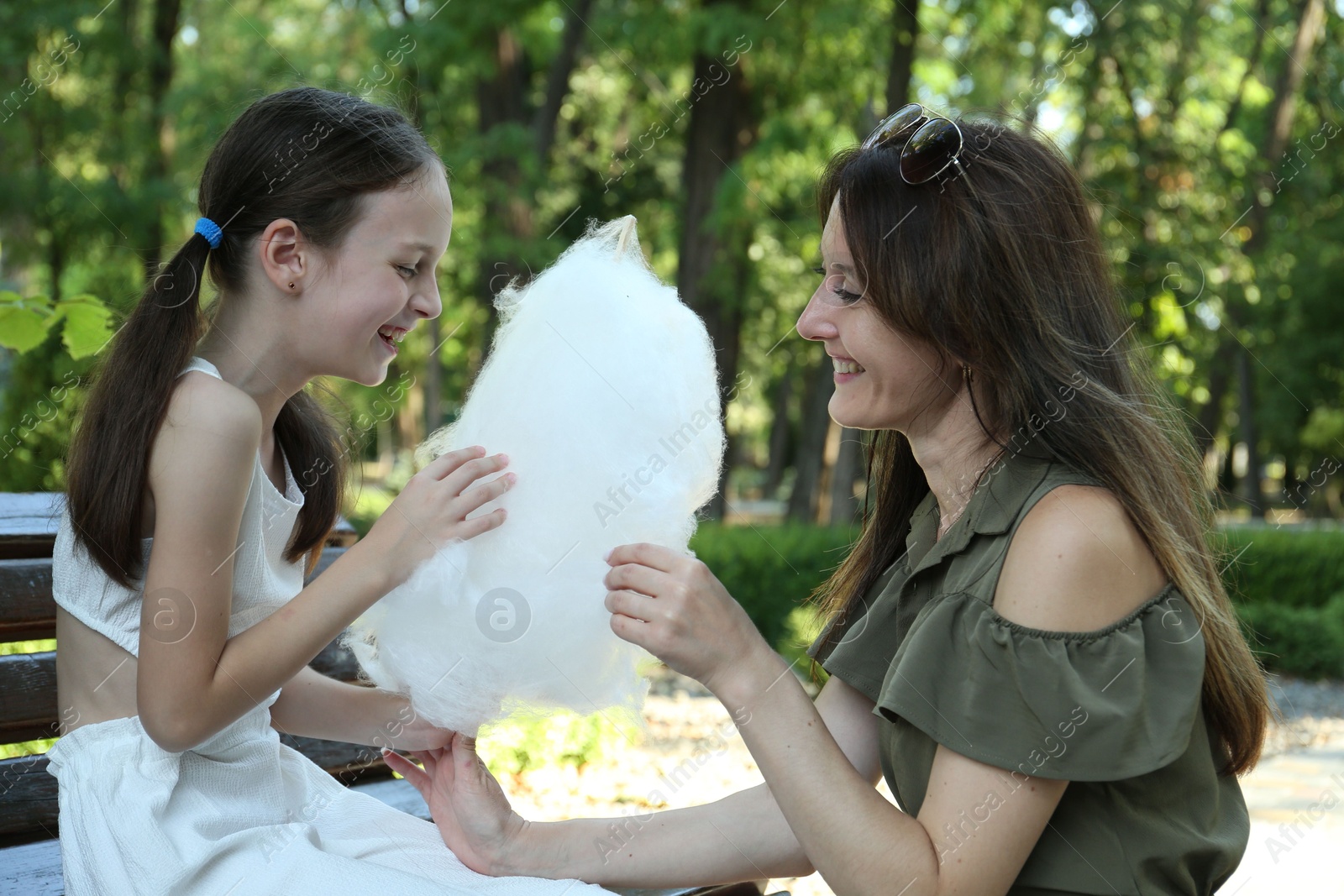 Photo of Happy mother and daughter eating sweet cotton candy in park