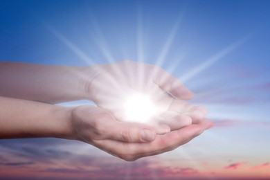 Image of Woman with holy light in hands against sky on sunrise, closeup