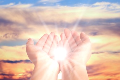 Image of Woman with holy light in hands against sky on sunrise, closeup