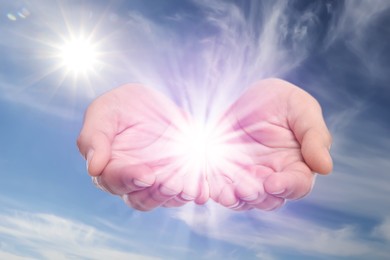 Man with holy light in hands against sky, closeup