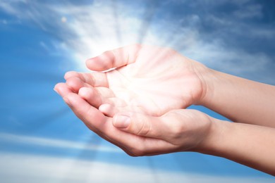 Image of Woman with holy light in hands against sky, closeup