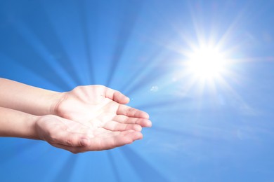 Woman with holy light in hands against sky, closeup