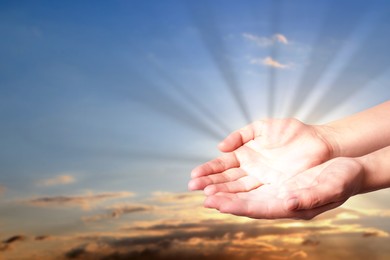 Image of Woman with holy light in hands against sky on sunrise, closeup