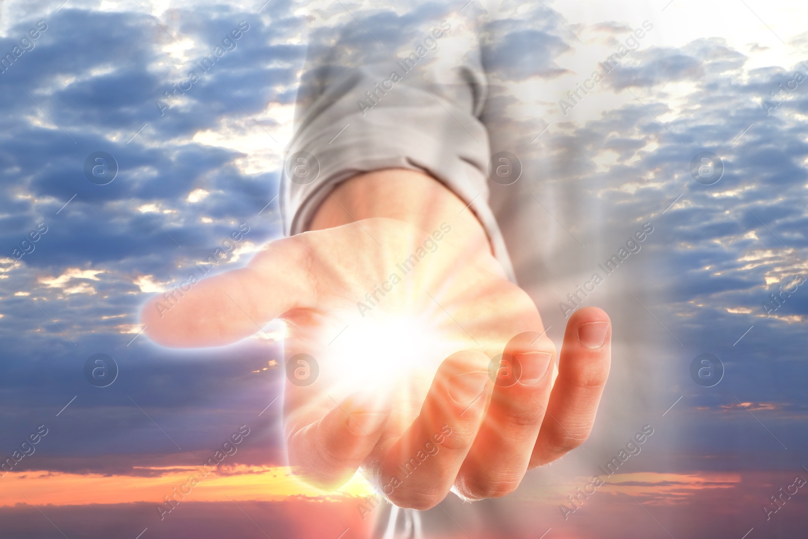 Image of Man with holy light in hand against sky on sunrise, closeup