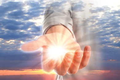 Image of Man with holy light in hand against sky on sunrise, closeup