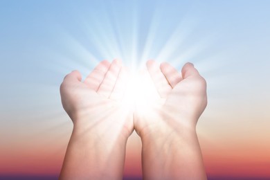 Image of Woman with holy light in hands against sky on sunrise, closeup