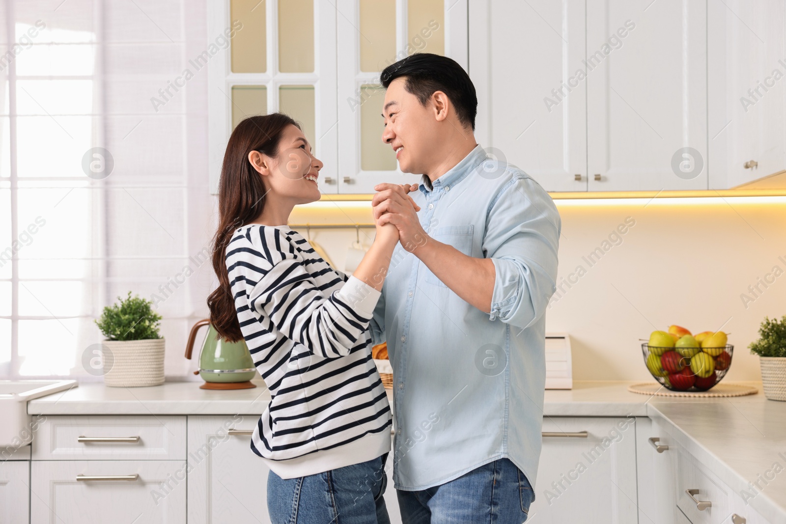 Photo of Happy lovely couple dancing together in kitchen