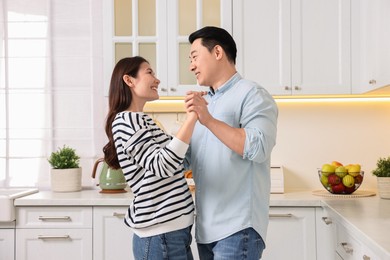 Happy lovely couple dancing together in kitchen