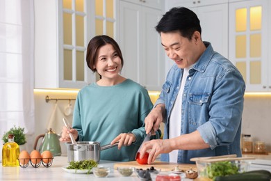 Photo of Happy lovely couple cooking together in kitchen