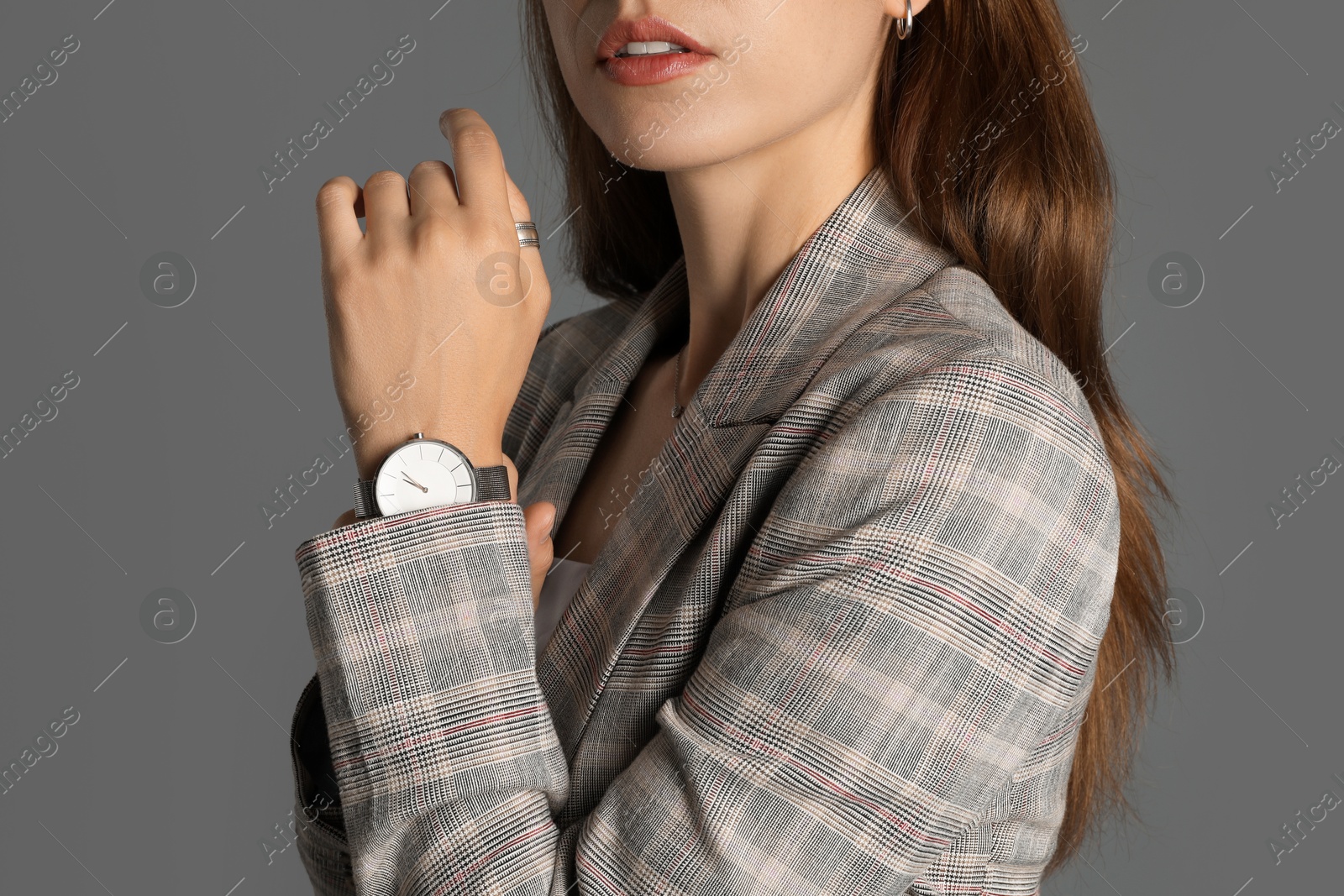 Photo of Beautiful woman with stylish jacket and watch on grey background, closeup