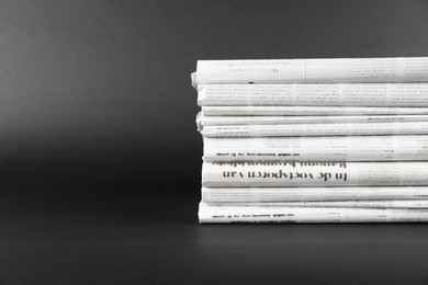 Stack of many newspapers in different languages on grey background, space for text