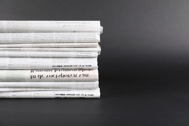 Stack of many newspapers in different languages on grey background, space for text