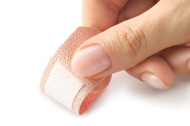 Photo of Woman putting medical adhesive bandage on white background, closeup