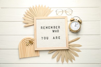 Flat lay composition of letter board with phrase Remember Who You Are on white wooden table