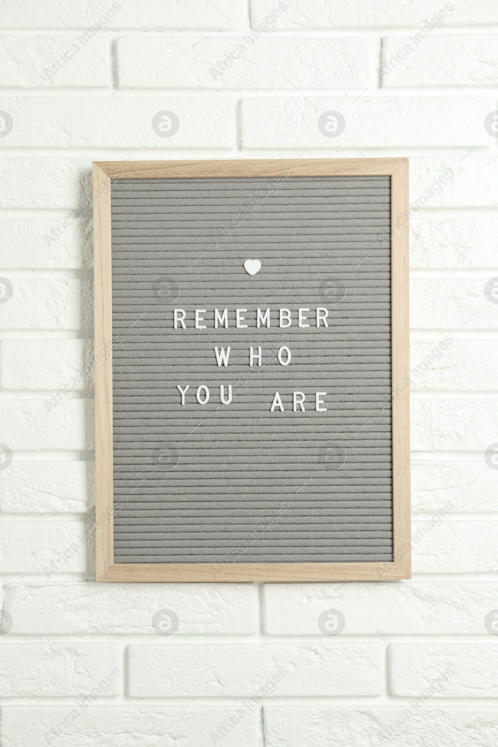 Photo of Letter board with phrase Remember Who You Are on white brick wall