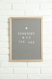 Letter board with phrase Remember Who You Are on white brick wall