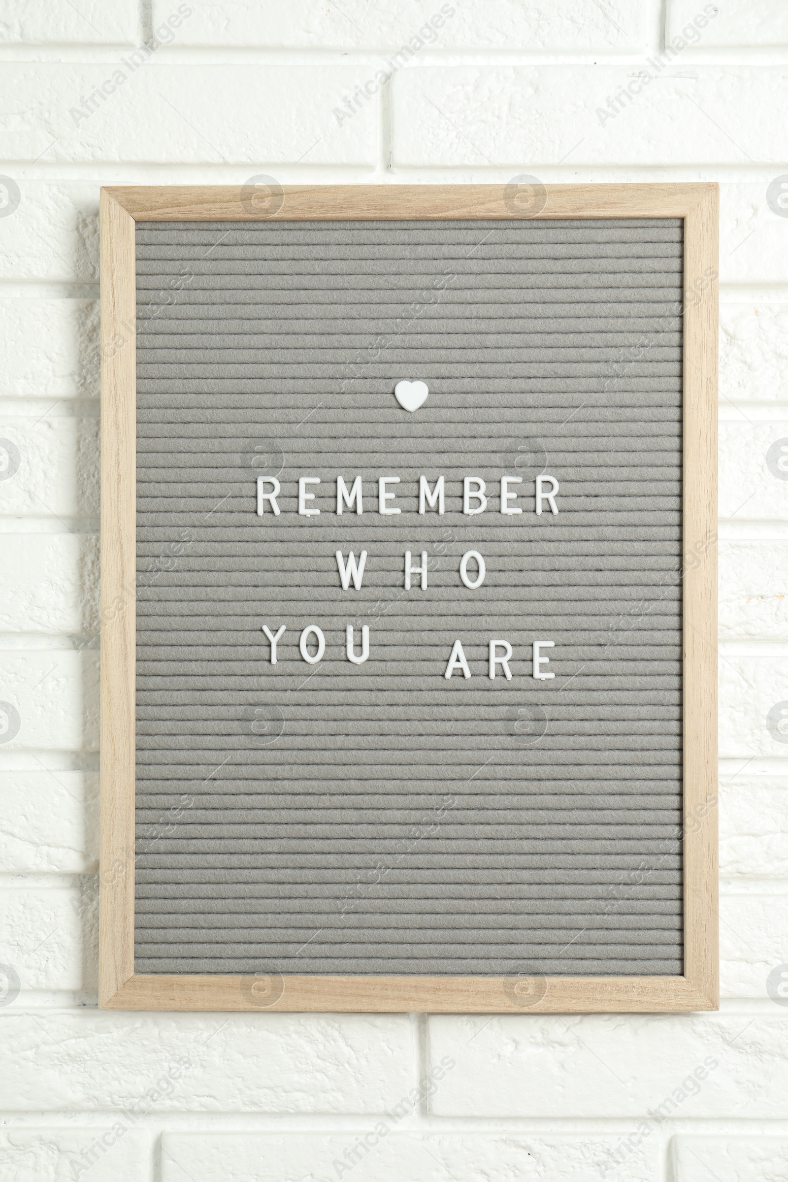 Photo of Letter board with phrase Remember Who You Are on white brick wall