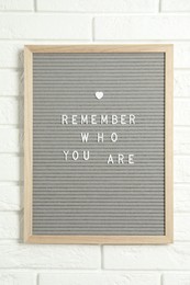 Letter board with phrase Remember Who You Are on white brick wall