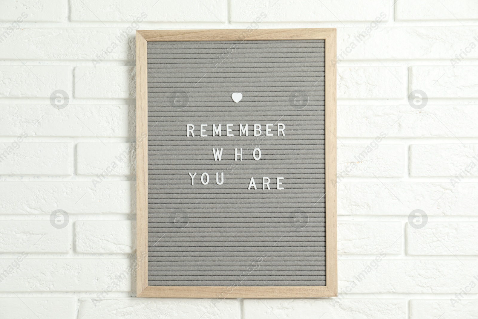 Photo of Letter board with phrase Remember Who You Are on white brick wall