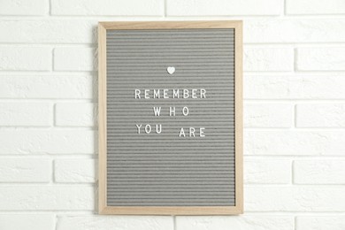 Photo of Letter board with phrase Remember Who You Are on white brick wall