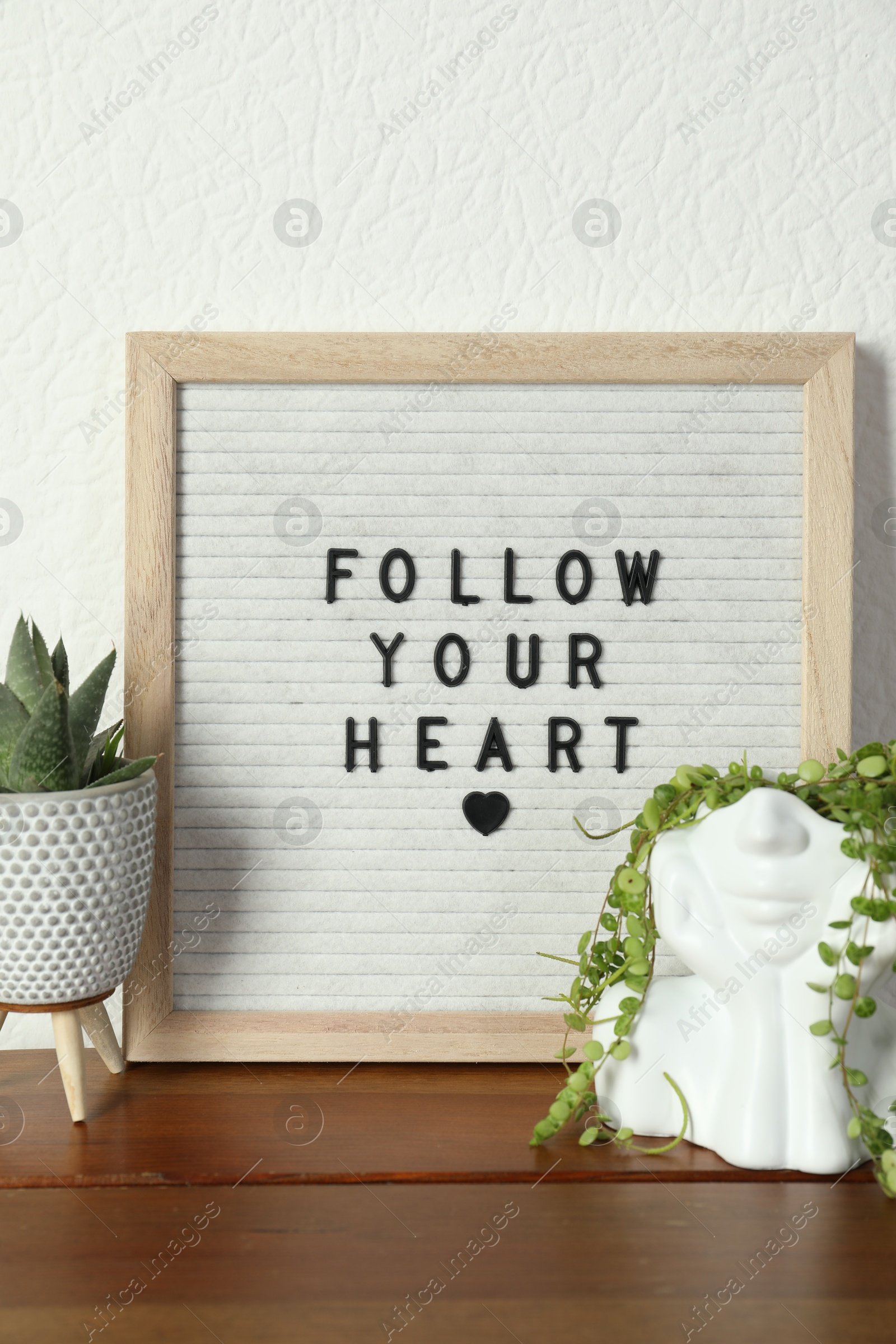 Photo of Letter board with phrase Follow Your Heart and plants on wooden table