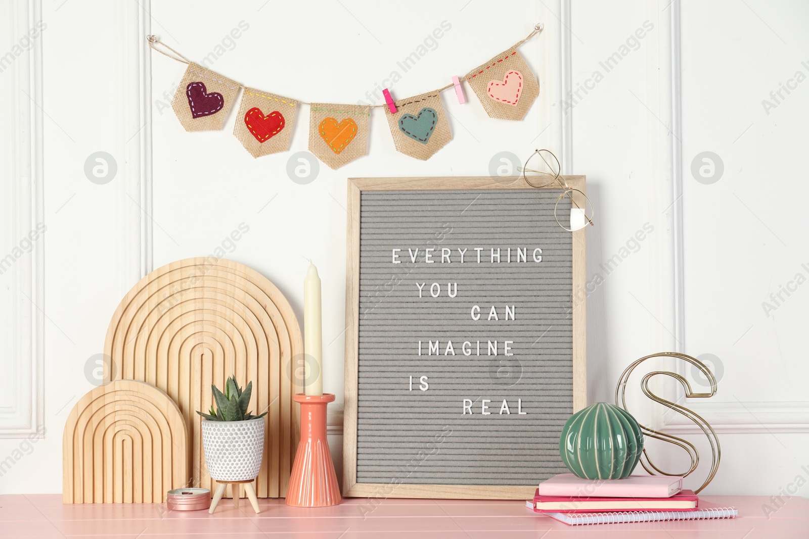 Photo of Letter board with phrase Everything You Can Imagine Is Real and decor elements on pink wooden table