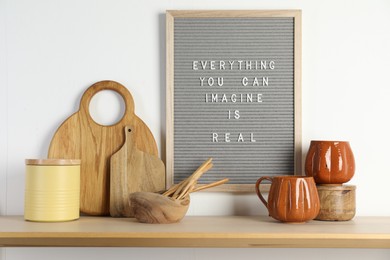 Photo of Letter board with phrase Everything You Can Imagine Is Real and beautiful dishware on wooden table