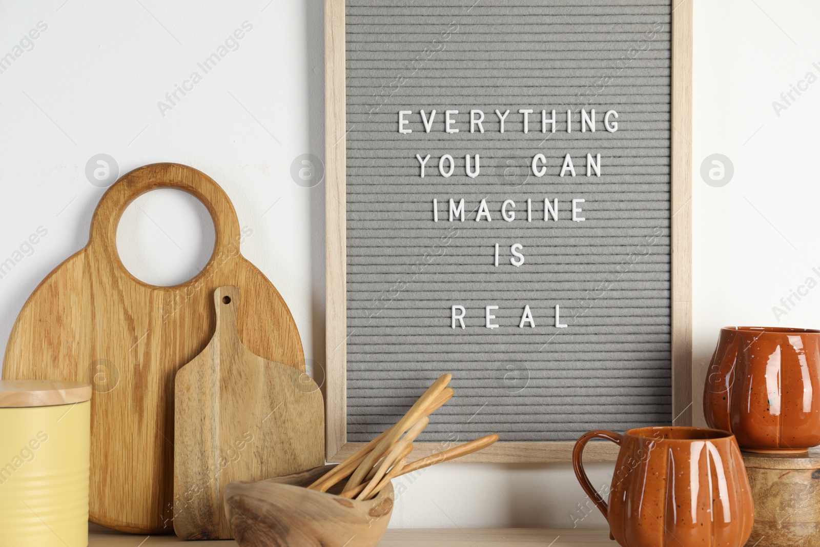 Photo of Letter board with phrase Everything You Can Imagine Is Real and beautiful dishware on wooden table