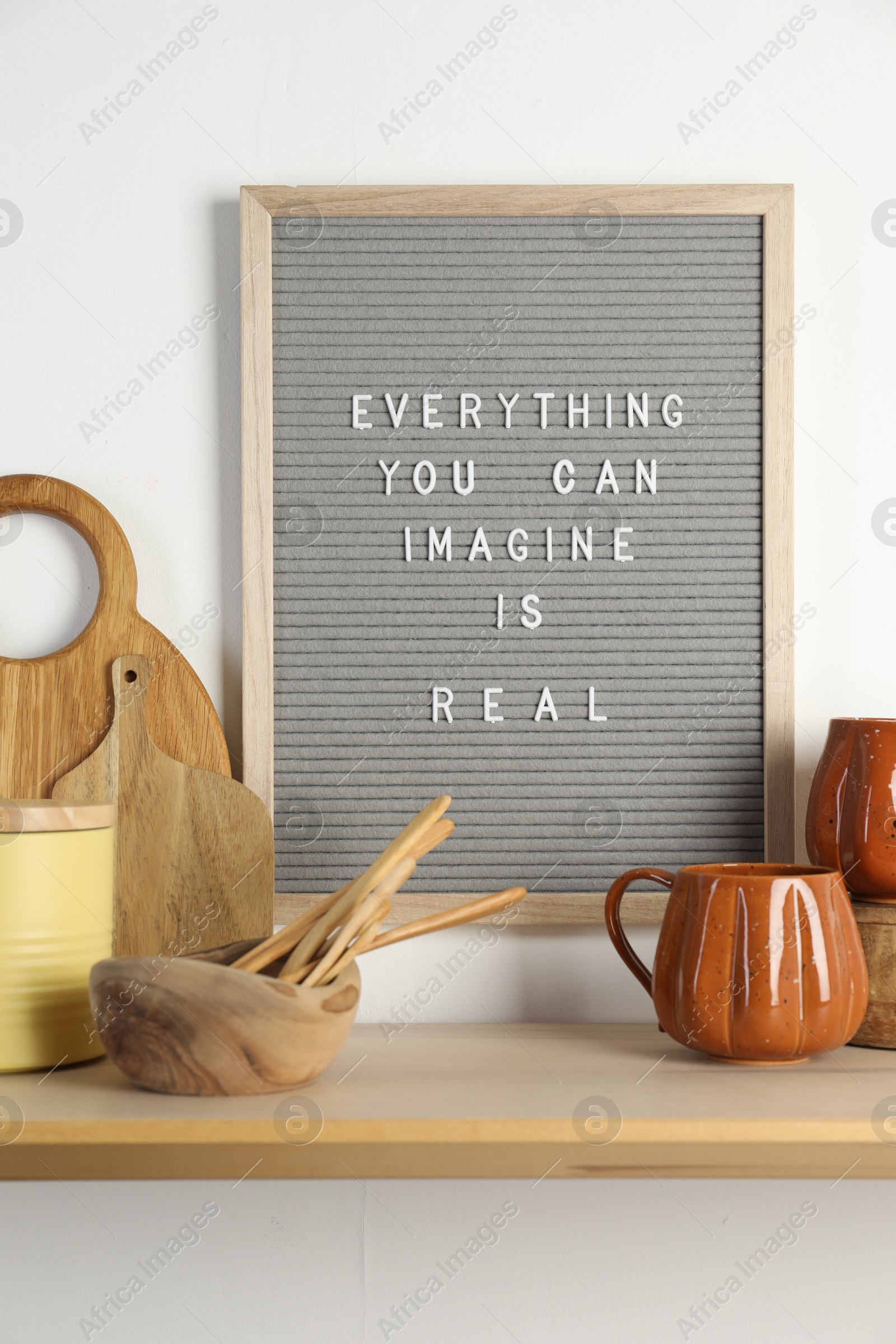 Photo of Letter board with phrase Everything You Can Imagine Is Real and beautiful dishware on wooden table