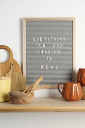 Photo of Letter board with phrase Everything You Can Imagine Is Real and beautiful dishware on wooden table