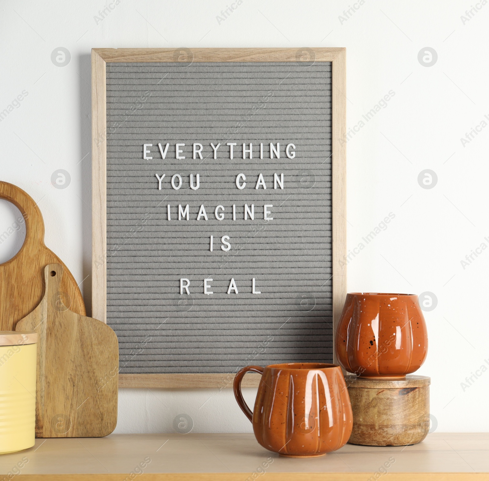 Photo of Letter board with phrase Everything You Can Imagine Is Real and beautiful dishware on wooden table. Space for text