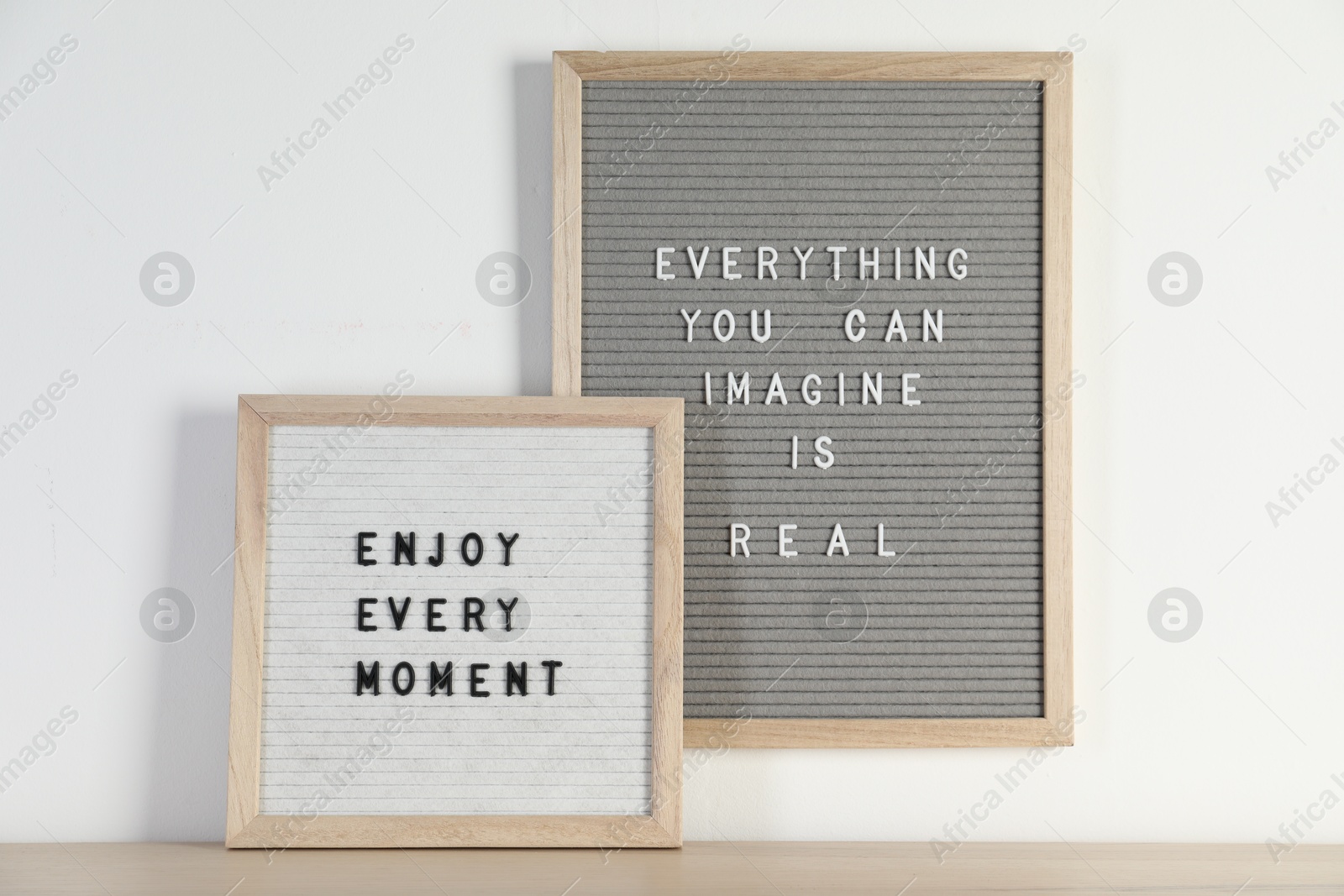 Photo of Letter boards with phrases Everything You Can Imagine Is Real and Enjoy Every moment on wooden table