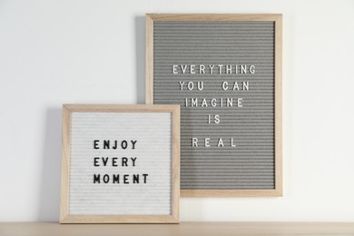 Photo of Letter boards with phrases Everything You Can Imagine Is Real and Enjoy Every moment on wooden table