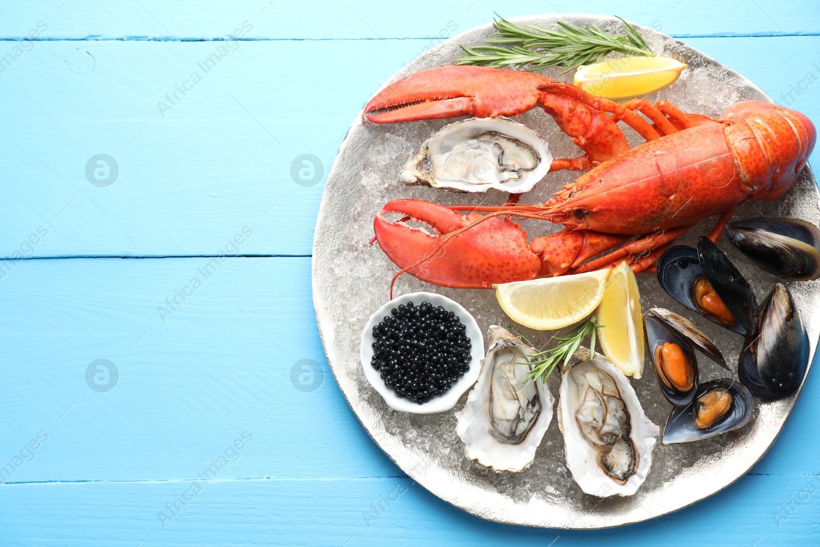 Photo of Many different sea food on light blue wooden table, top view. Space for text