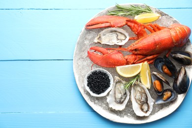 Many different sea food on light blue wooden table, top view. Space for text