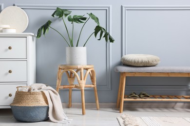 Photo of Stylish interior with stool and chest of drawers near light grey wall