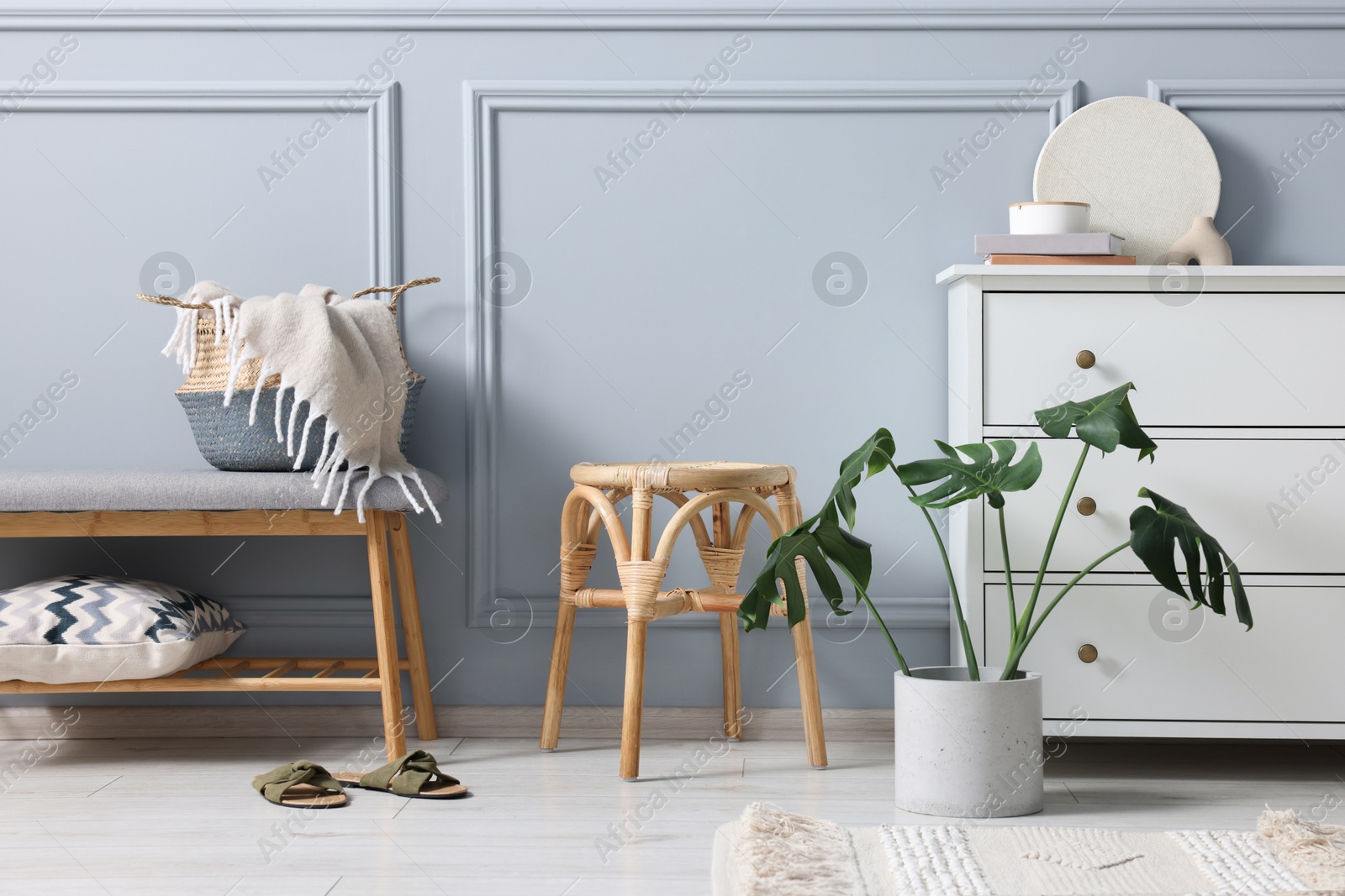 Photo of Stylish interior with stool and chest of drawers near light grey wall