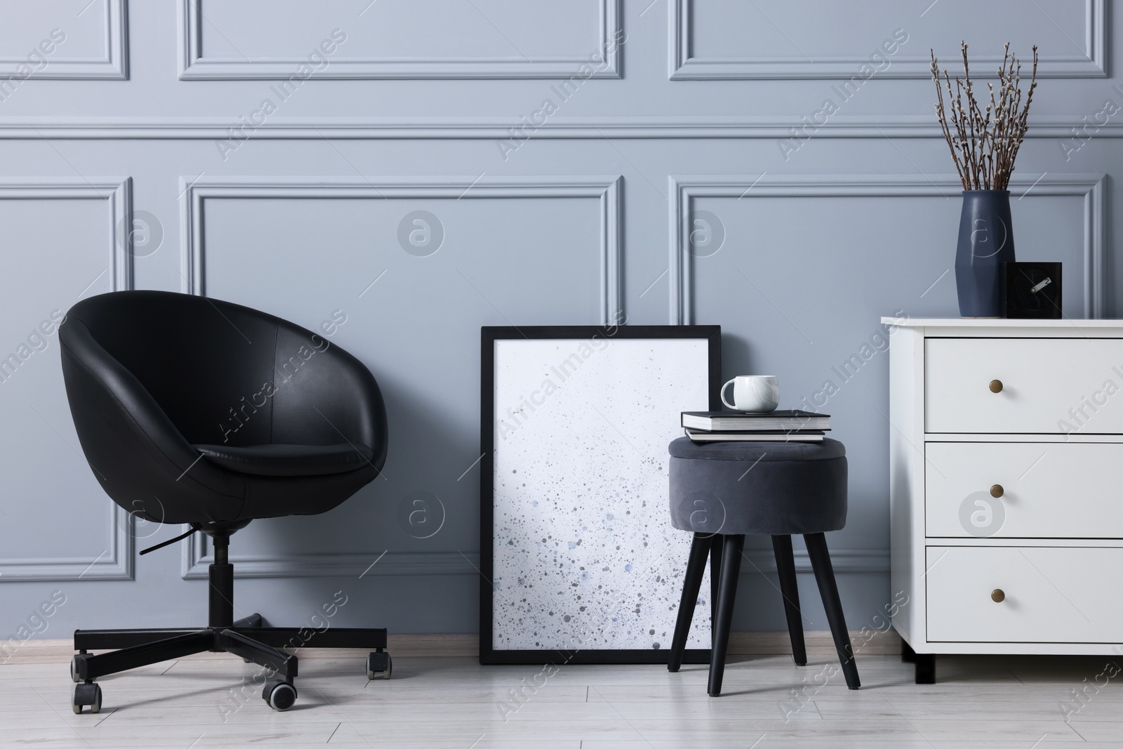 Photo of Stylish interior with stool and chest of drawers near light grey wall