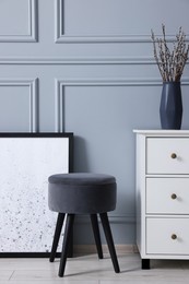 Photo of Stylish interior with stool and chest of drawers near light grey wall